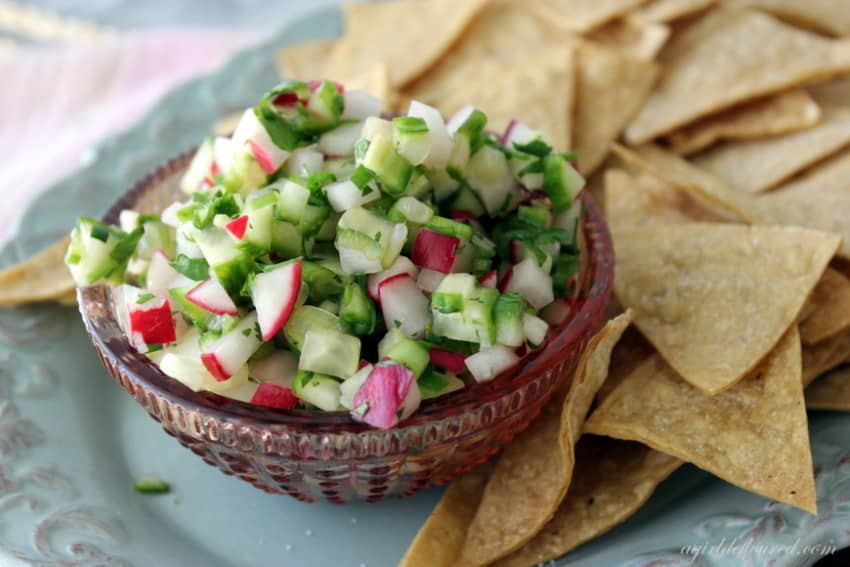 a bowl of radish cucumber salsa surrounded by tortilla chips