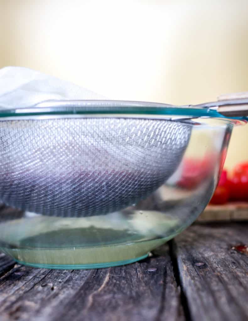 tomato water recipe - tomato water coming through a strainer