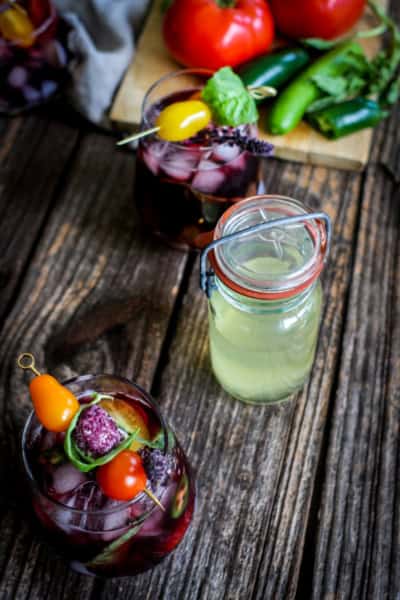 two cocktail made with tomato water, and a jar of clear tomato juice