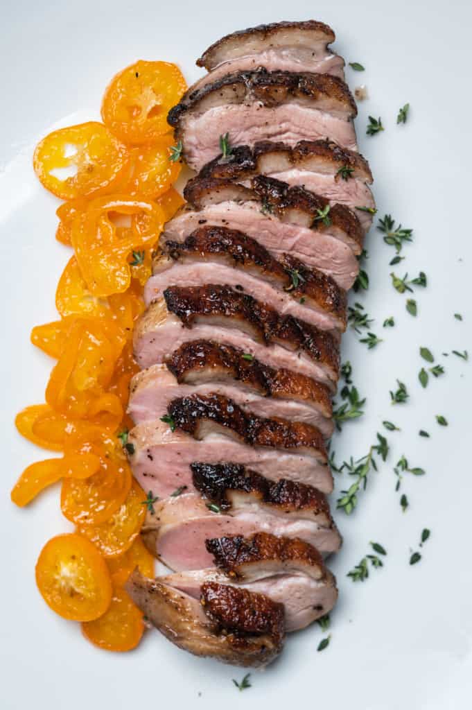 a beautifully cooked duck breast cut into slices served with kumquats