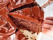 Removing a slice of Devil's Food Cake from a whole chocolate cake with chocolate frosting