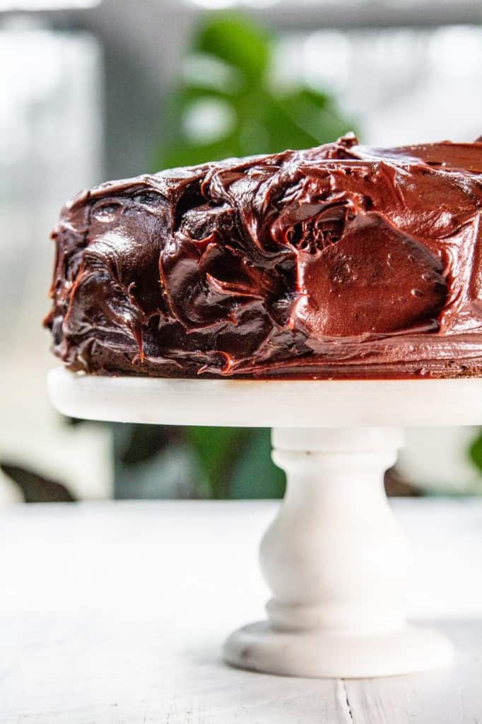 Chocolate cake displayed on a white marble cake stand