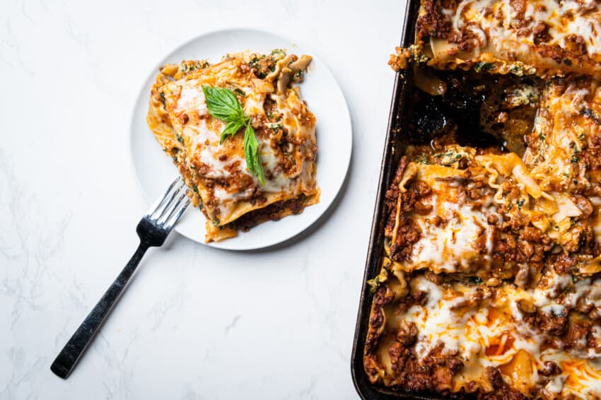 A plate of lasagna next to the pan of lasagna