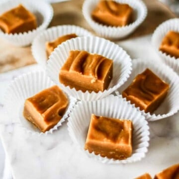 cubes of peanut butter fudge in cupcake cups on a marble slab