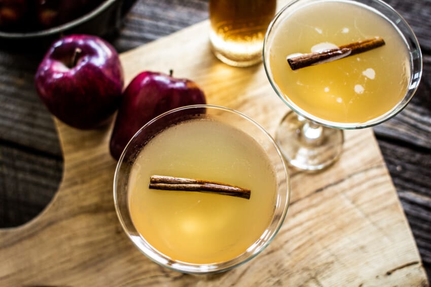 Two apple martinis on a wooden background with apples in the background