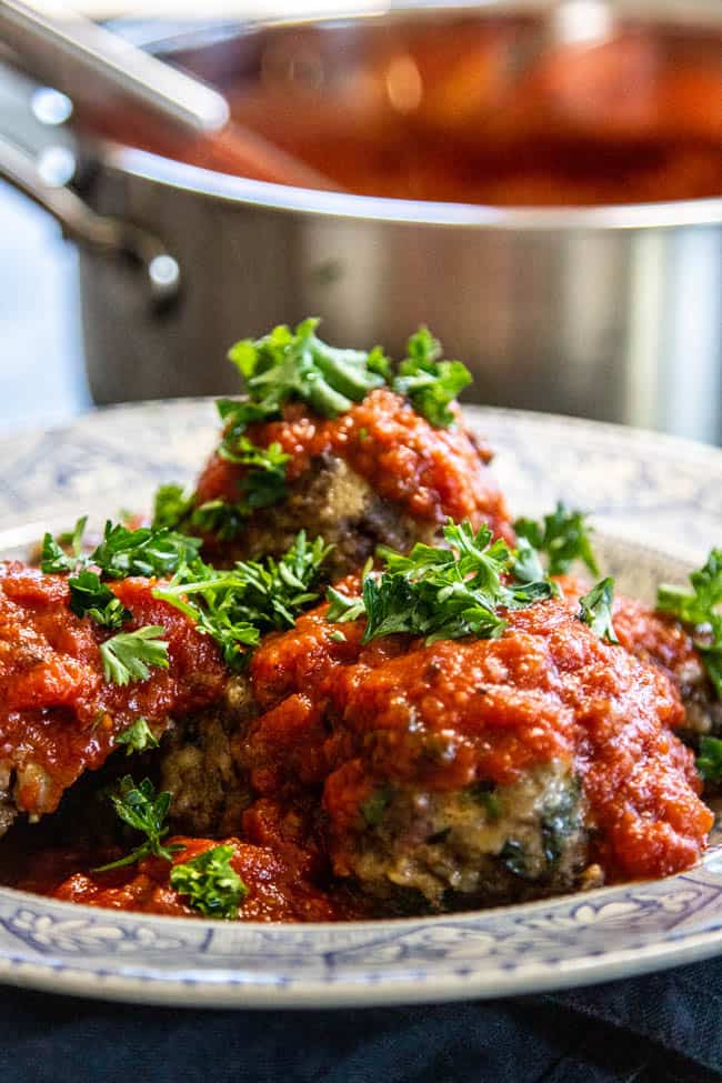 a plate with meatballs topped with marinara & fresh herbs