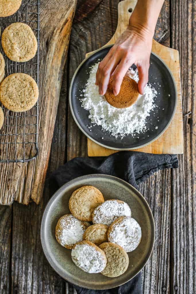 hand dipping cookies into topping in front of plate of cookies