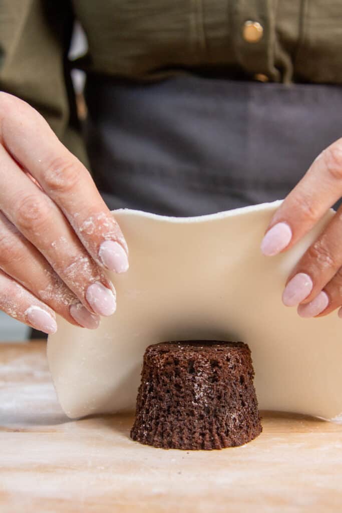 hand placing fondant on to cake