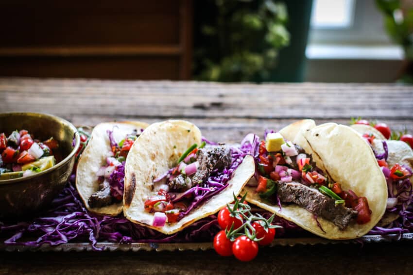 steak tacos on a wooden background with  fresh tomatoes
