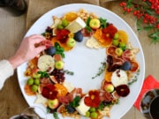 charcuterie wreath with red wine and hand reaching in