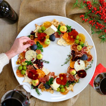charcuterie wreath with red wine and hand reaching in
