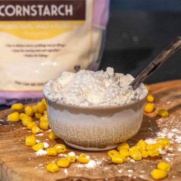 A bowl of cornstarch on a wooden cutting board