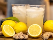 two glasses of ginger beer surrounded lemons and ginger