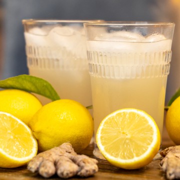 two glasses of ginger beer surrounded lemons and ginger