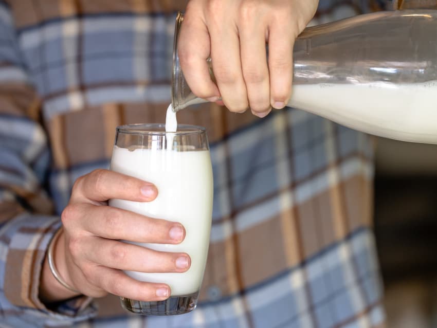 person pouring a glass of milk