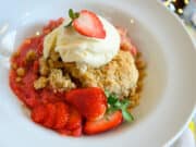 bowl of Strawberry Rhubarb Crisp with ice cream and fresh berries