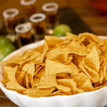 Tortilla chips with tequila and lime in the background