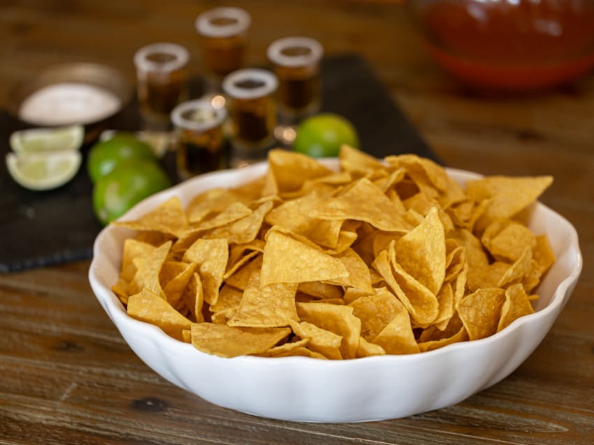 bowl of tortilla chips lined up with shots of tequila