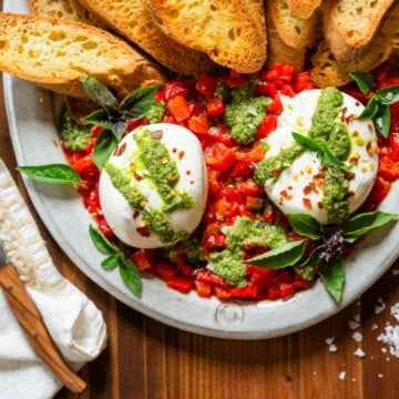 burrata appetizer recipe on platter with pesto and red peppers
