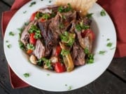 shredded lamb shoulder in a serving bowl with peppers and garlic - lamb shoulder cooked in the oven