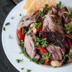 shredded lamb shoulder recipe with vegetables and parsley on a plate